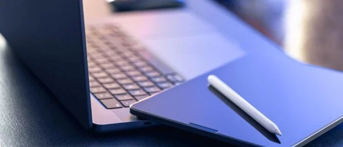 un_stylet_de_tablette_numérique_et_un_ordinateur_portable_sur_le_bureau_en_gros_plan